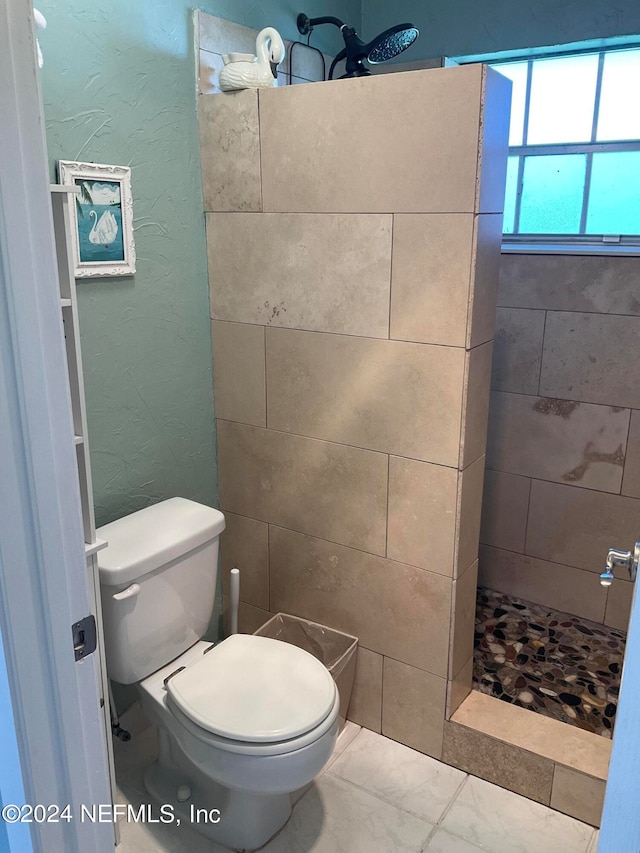 bathroom featuring a tile shower and toilet