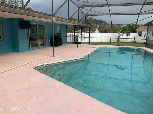 view of swimming pool featuring a patio area and a lanai