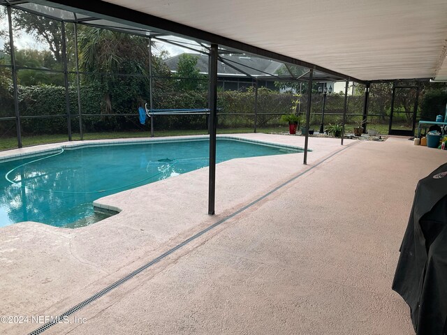 view of swimming pool featuring a patio and glass enclosure