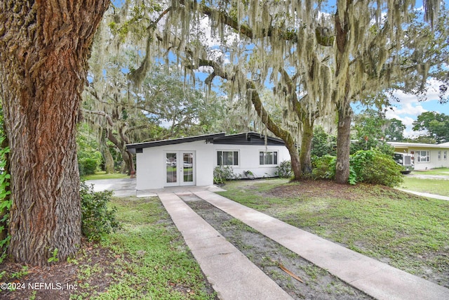 view of front of property featuring a front yard and french doors