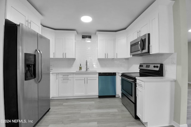 kitchen with stainless steel appliances, sink, light wood-type flooring, and white cabinetry