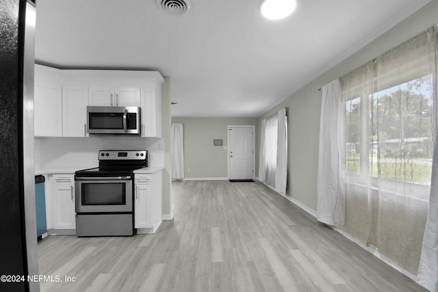 kitchen featuring light wood-type flooring, stainless steel appliances, white cabinets, and decorative backsplash