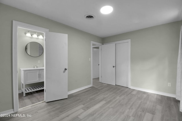 unfurnished bedroom featuring light wood-type flooring, a closet, and connected bathroom