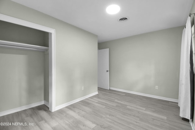 unfurnished bedroom featuring light wood-type flooring and a closet