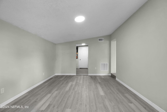 unfurnished room with a textured ceiling and light hardwood / wood-style floors