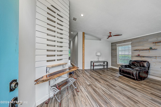 interior space with wood walls, ceiling fan, hardwood / wood-style flooring, and a textured ceiling