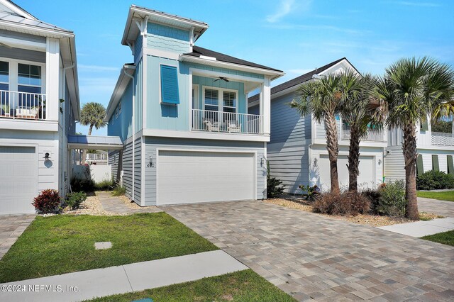 coastal inspired home featuring a balcony, ceiling fan, and a garage