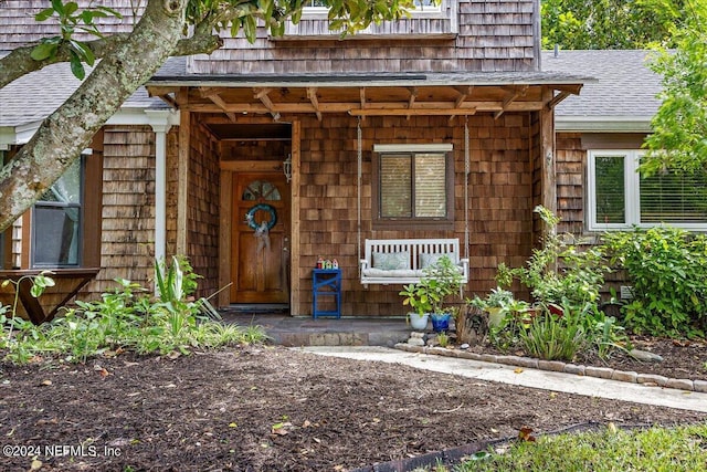 view of exterior entry featuring a shingled roof