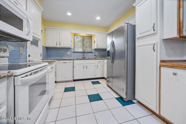 kitchen featuring white appliances, light tile patterned floors, tasteful backsplash, sink, and white cabinets