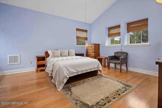 bedroom featuring high vaulted ceiling and light hardwood / wood-style flooring