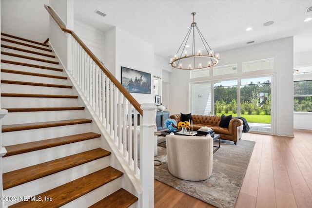 interior space featuring light wood-type flooring, a notable chandelier, and a textured ceiling