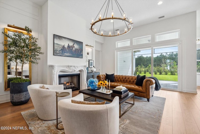 living room with a fireplace, hardwood / wood-style floors, a high ceiling, a textured ceiling, and a chandelier