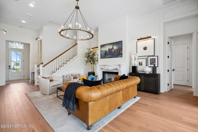 living room featuring light hardwood / wood-style flooring, a high end fireplace, and an inviting chandelier