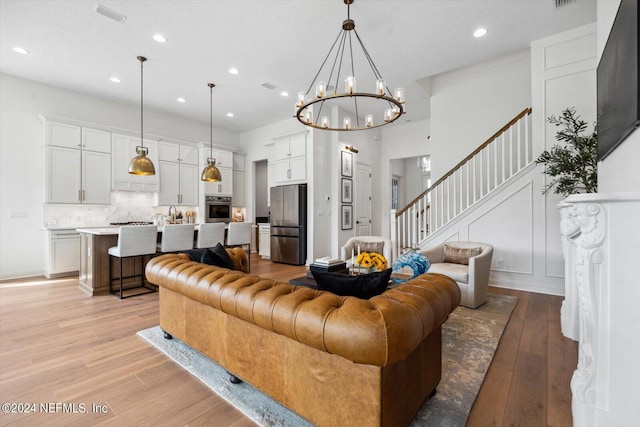 living room featuring a textured ceiling, a notable chandelier, and light hardwood / wood-style floors