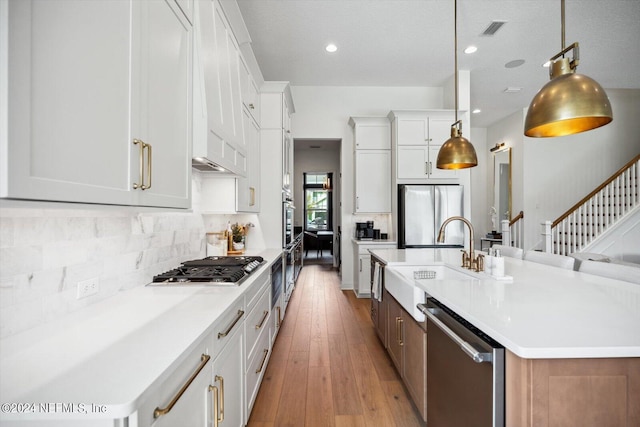 kitchen with stainless steel appliances, decorative light fixtures, and white cabinets