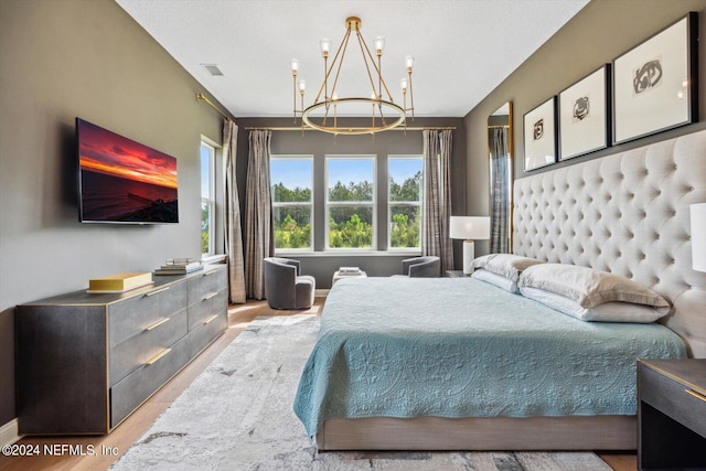 bedroom featuring a textured ceiling, a chandelier, and light hardwood / wood-style floors