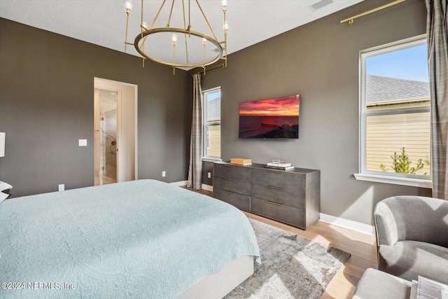 bedroom with light hardwood / wood-style flooring and an inviting chandelier