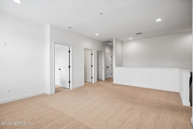 empty room featuring light carpet and a textured ceiling