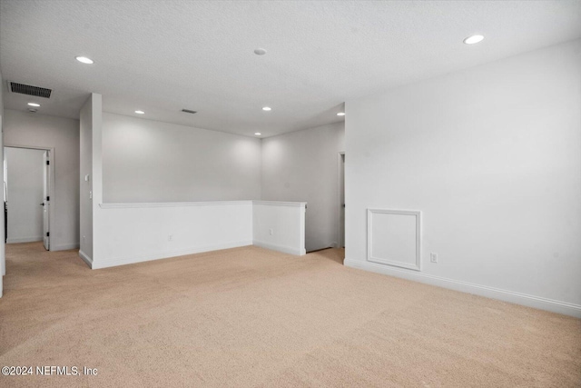 unfurnished room featuring light carpet and a textured ceiling