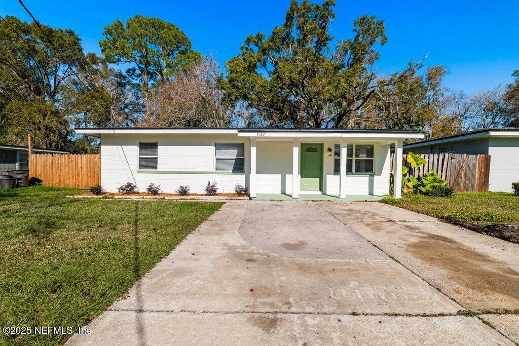 ranch-style house featuring covered porch and a front yard