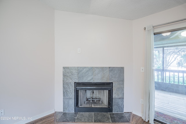 interior details with a textured ceiling, hardwood / wood-style floors, and a tile fireplace