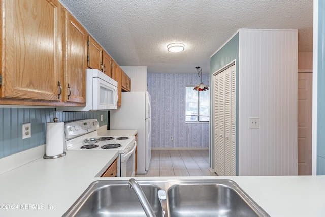 kitchen with white appliances, light hardwood / wood-style floors, sink, pendant lighting, and a textured ceiling