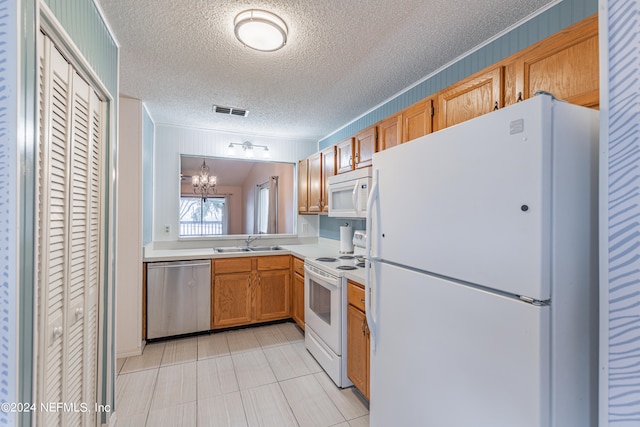 kitchen with light tile patterned floors, white appliances, a chandelier, sink, and a textured ceiling