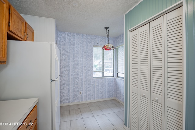 kitchen featuring light tile patterned floors, hanging light fixtures, white fridge, and a textured ceiling