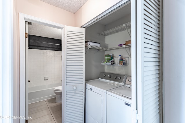 laundry room featuring separate washer and dryer, a textured ceiling, and light tile patterned flooring