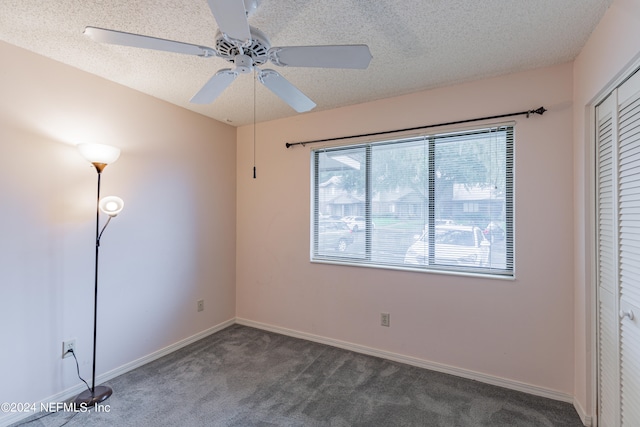 unfurnished bedroom featuring a textured ceiling, dark carpet, ceiling fan, and a closet