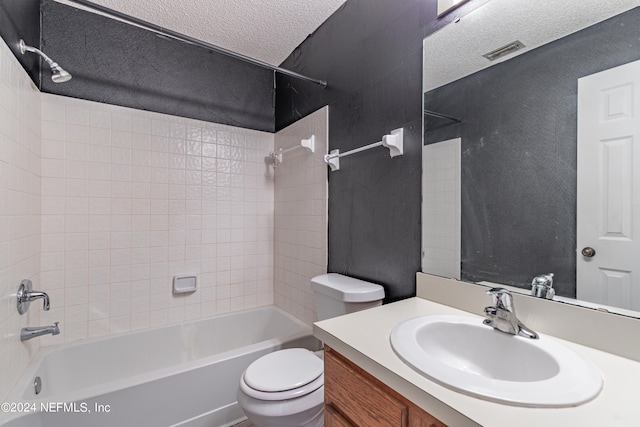 full bathroom featuring tiled shower / bath, vanity, toilet, and a textured ceiling