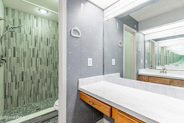 bathroom with tiled shower, toilet, a textured ceiling, and vanity