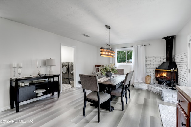 dining space with separate washer and dryer, a textured ceiling, hardwood / wood-style floors, and a wood stove