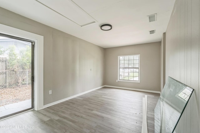 unfurnished room with wood walls and light wood-type flooring