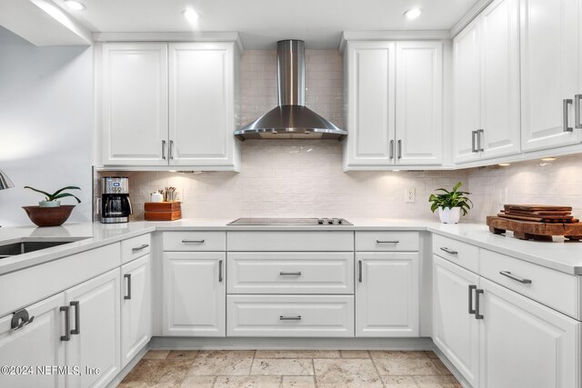 kitchen featuring white cabinets, black electric stovetop, wall chimney range hood, and backsplash