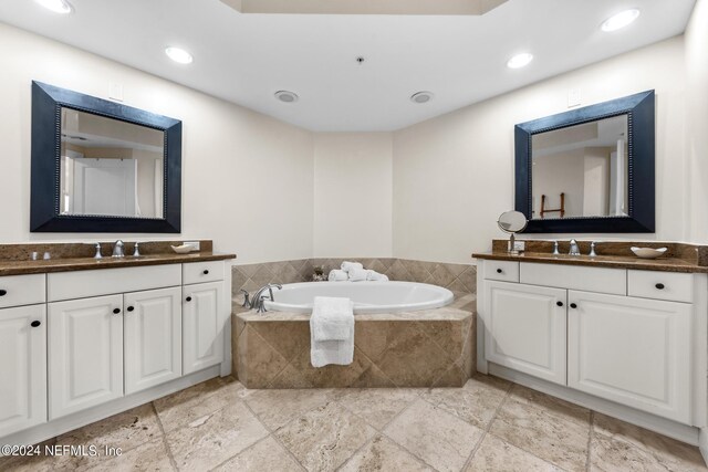 bathroom with vanity and tiled bath