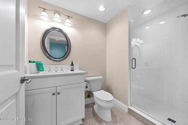 bathroom featuring tile patterned floors, vanity, toilet, and a shower with door