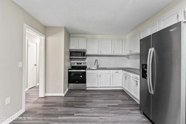 kitchen with white cabinetry, dark wood-type flooring, stainless steel appliances, and sink