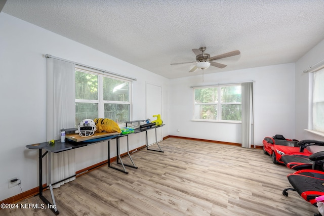 misc room with ceiling fan, a textured ceiling, light hardwood / wood-style flooring, and a wealth of natural light