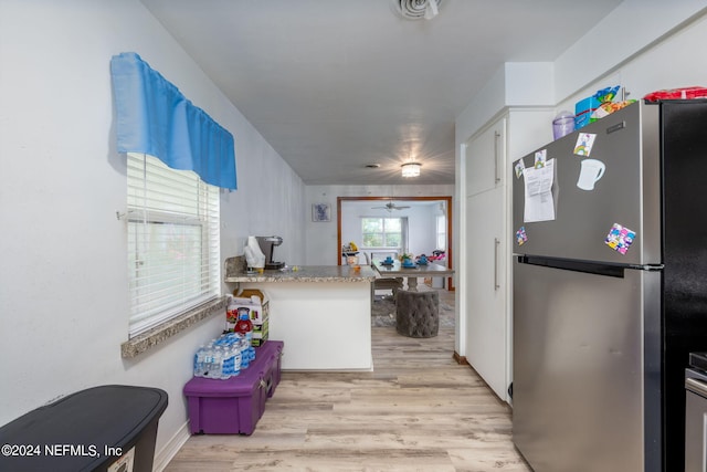 kitchen featuring white cabinets, stainless steel refrigerator, kitchen peninsula, light wood-type flooring, and ceiling fan