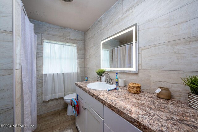 bathroom with vanity, tile walls, and toilet