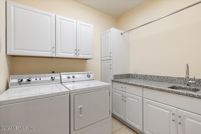 washroom featuring washer and dryer, sink, and cabinets