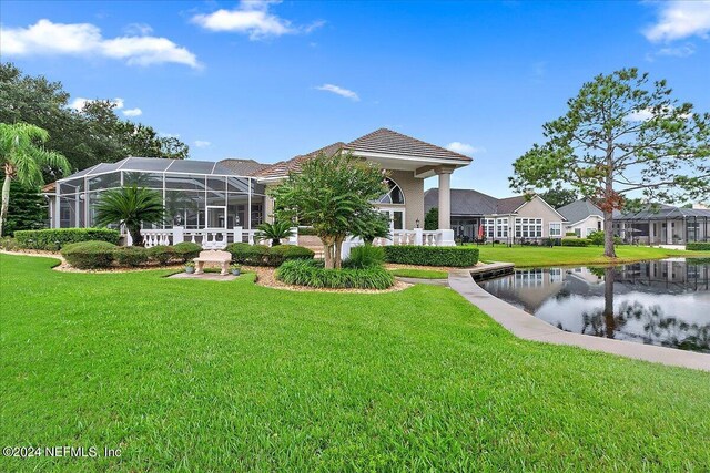 rear view of house with a yard and a lanai