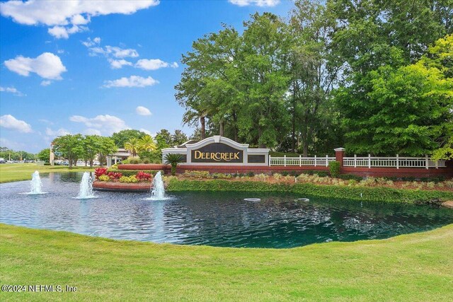 community sign featuring a water view and a yard