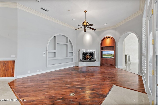 unfurnished living room featuring crown molding, wood-type flooring, built in features, and ceiling fan