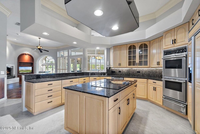 kitchen with sink, appliances with stainless steel finishes, dark stone countertops, a center island, and light brown cabinets