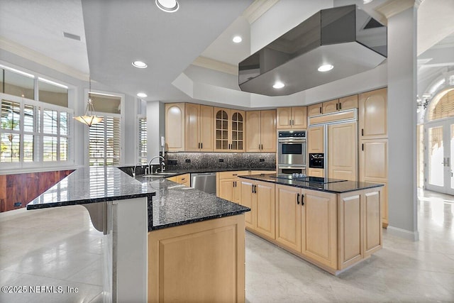 kitchen featuring sink, stainless steel appliances, a kitchen island, dark stone counters, and light brown cabinets