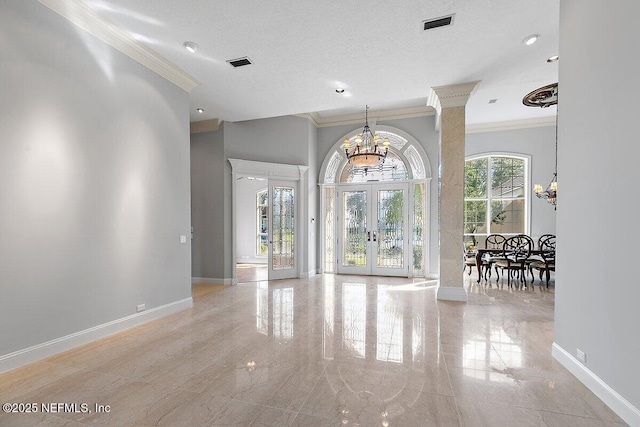 interior space with ornate columns, an inviting chandelier, ornamental molding, a textured ceiling, and french doors