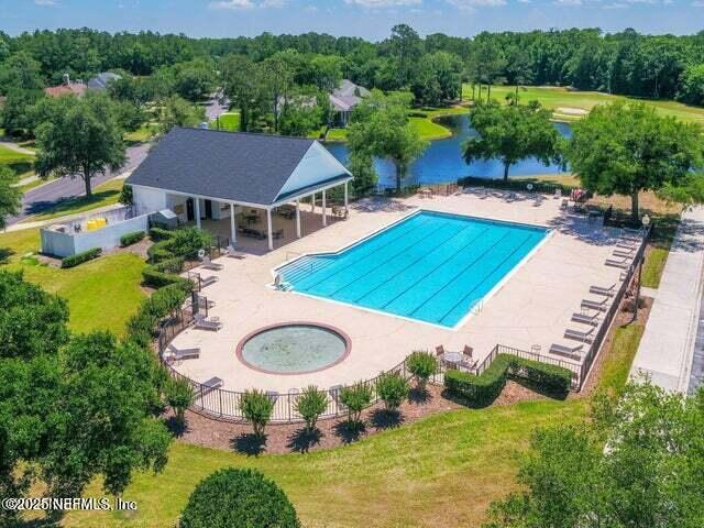 view of swimming pool featuring a patio, a water view, and a yard