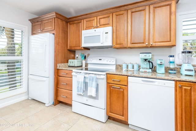 kitchen featuring white appliances, light tile patterned floors, and light stone countertops